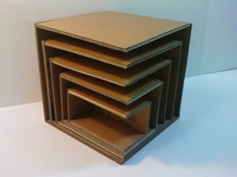 Five nested cardboard boxes of progressively smaller sizes are stacked inside each other, creating a tiered, concentric arrangement. This art object is displayed on a white surface with a plain background.