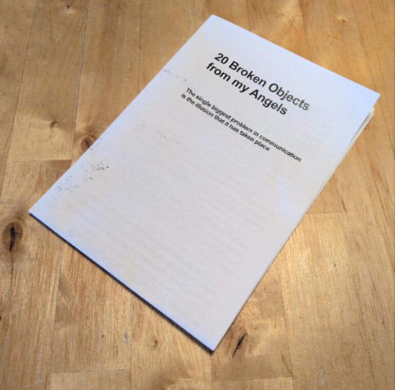 A booklet titled "20 Broken Objects from my Angels" lies on a wooden surface. The cover also reads, "The Hello, Bauer problem in communication & the situation that I have stolen piece.